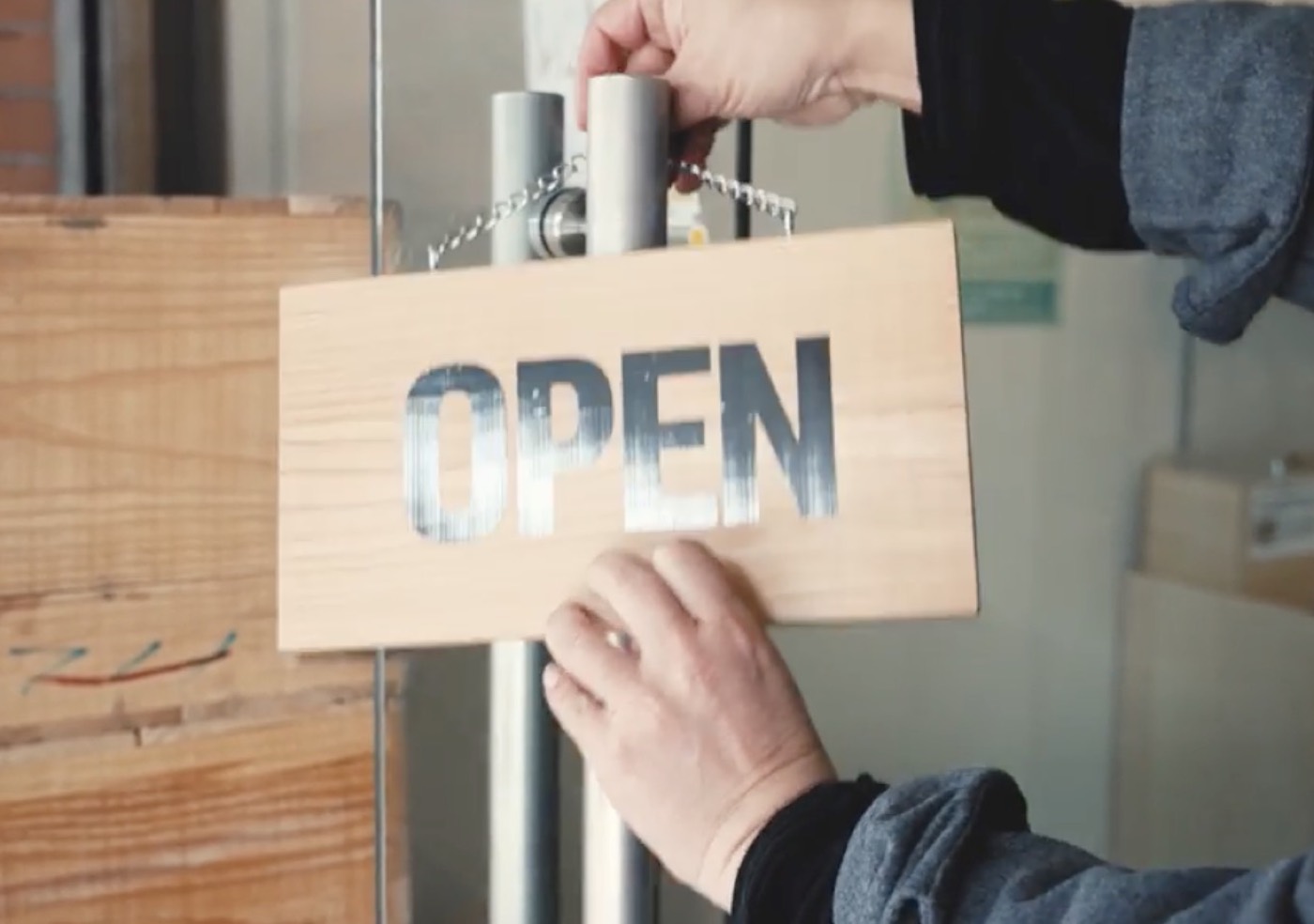 店の扉に、OPENの札をかける手元