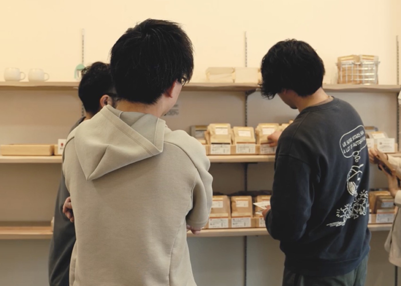 商品の棚の前で、話し合いながら見ている人たち